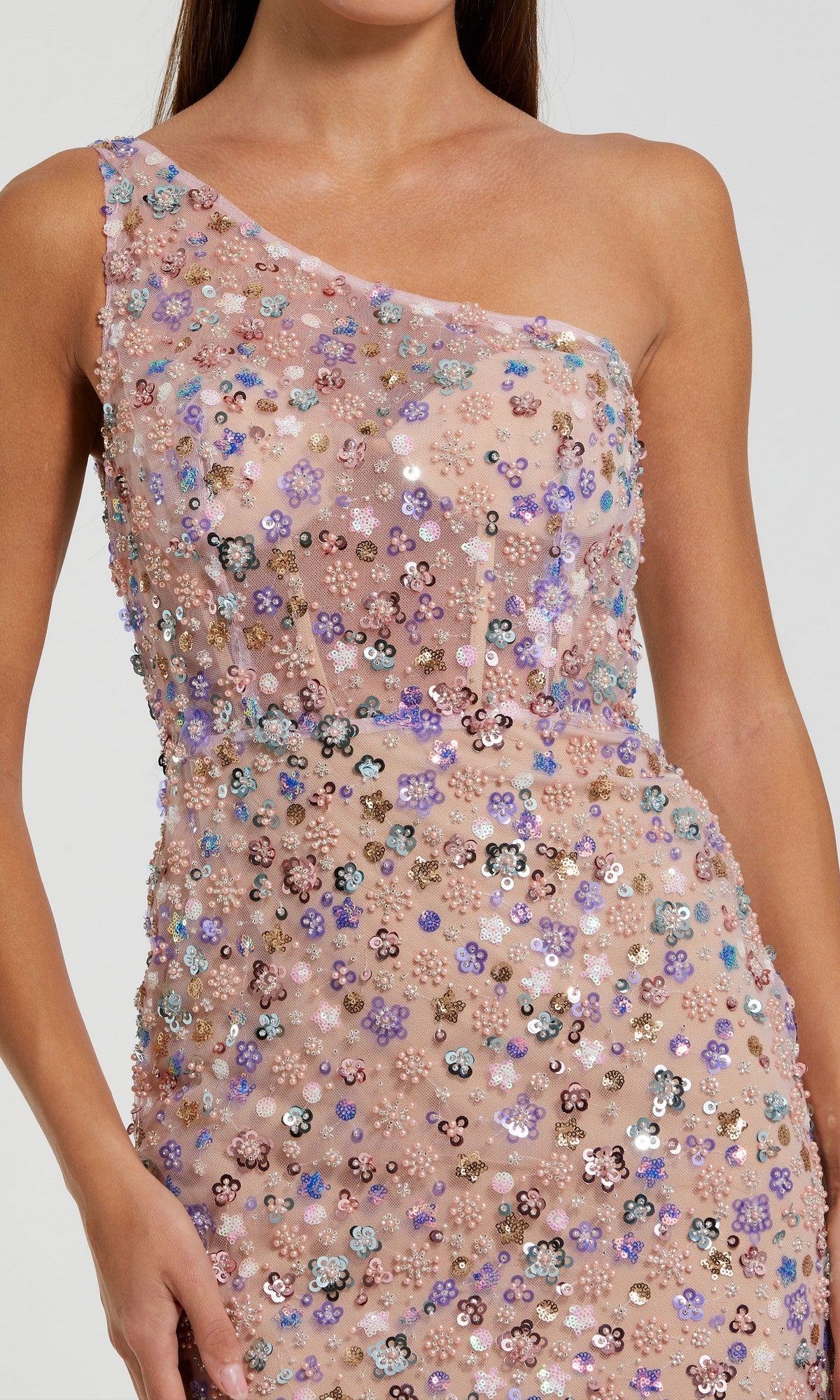 A woman in the Mac Duggal 68889 long prom dress showcases a sleeveless, one-shoulder neckline with multicolored floral sequins on nude mesh fabric.